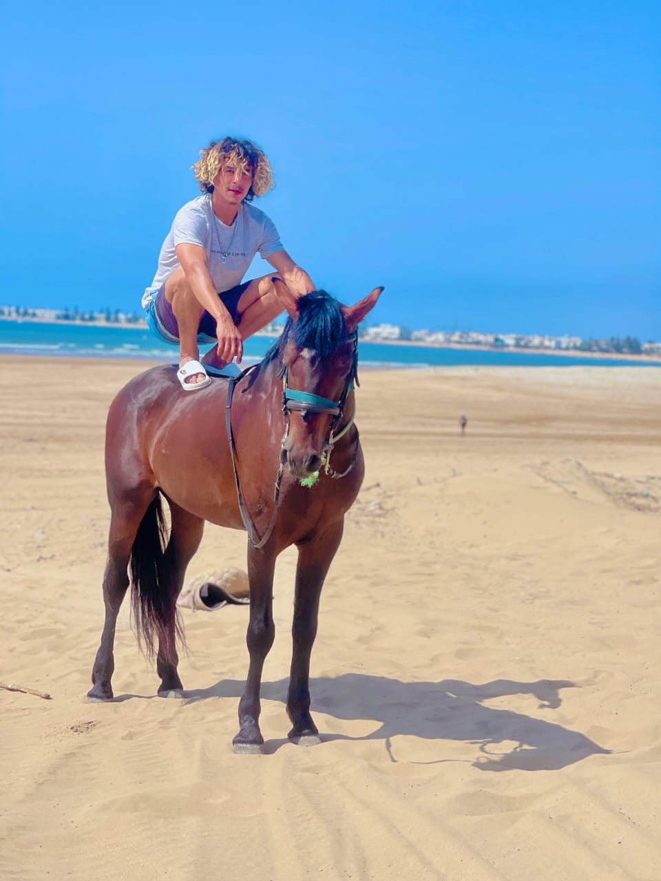 Mokhtar accroupi sur le dos d'Assif sur la plage