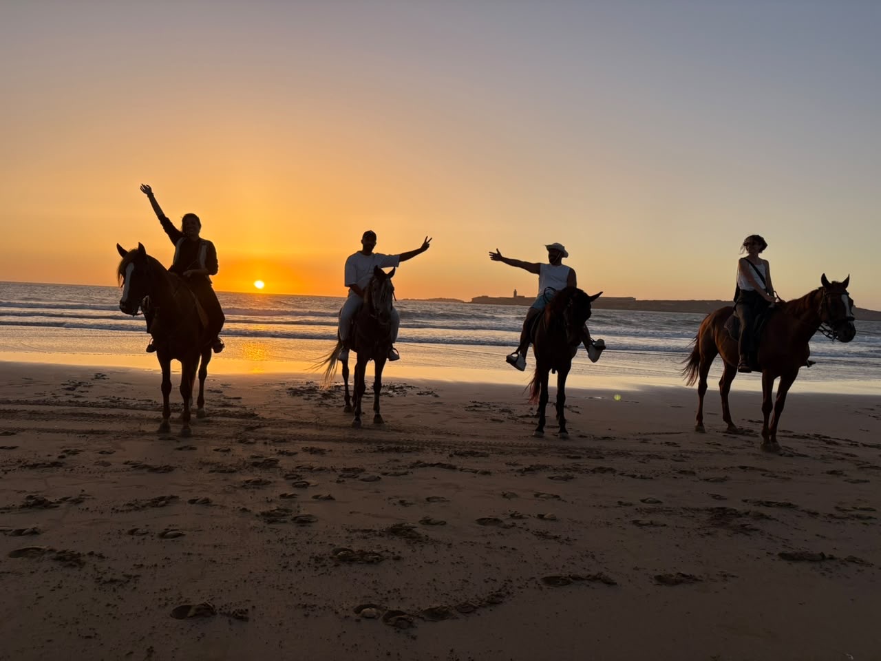 Four riders celebrating as the sun sets over the Atlantic
