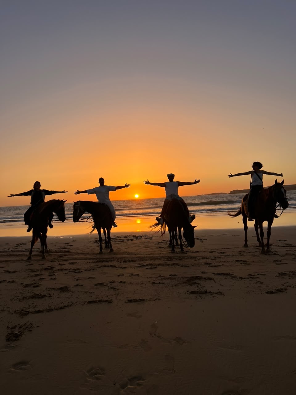 Riders with arms outstretched at sunset on Essaouira beach