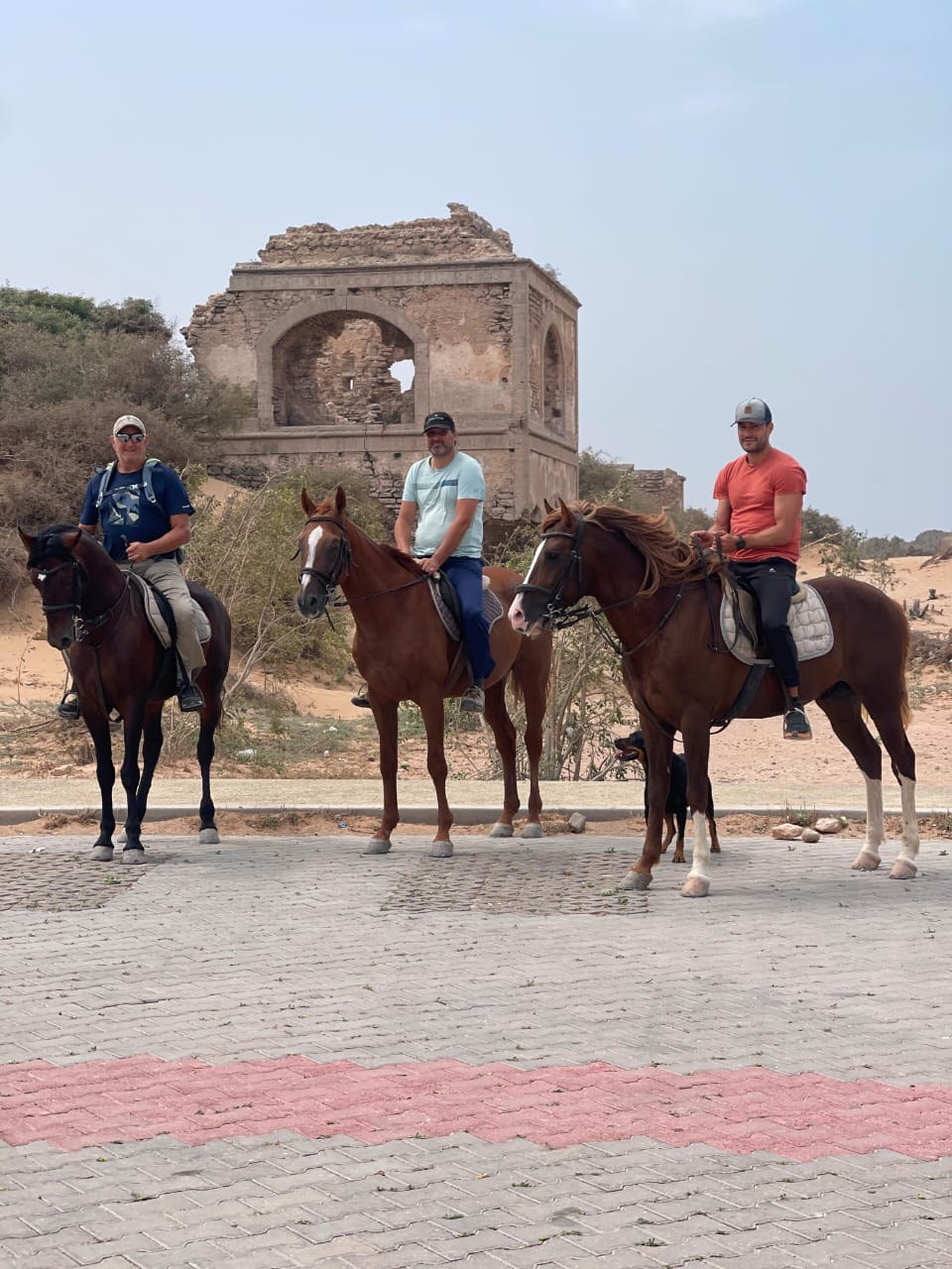 Riders resting by old ruins near the dunes